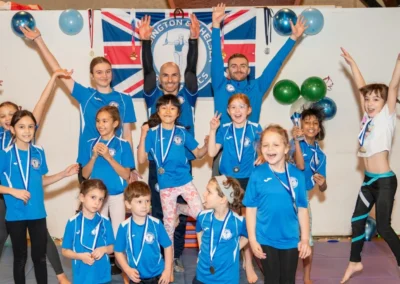 Children and coaches celebrating with medals at KCGA Christmas 2024 gymnastics event in Kensington London