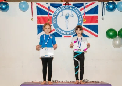 Two girls holding gymnastics certificates and medals at KCGA Christmas event in London