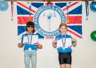 Two young girls showing gymnastics medals at KCGA London Christmas celebration