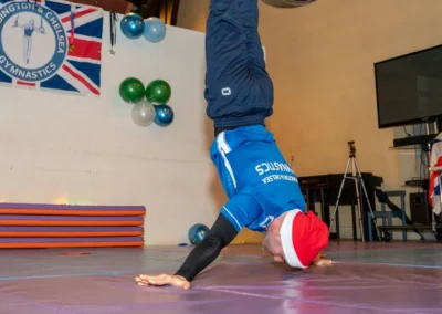 Gymnastics coach assisting young gymnast during split exercise at KCGA Christmas event London
