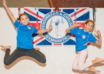 Two girls jumping with medals at London gymnastics club Christmas celebration