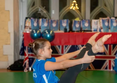 Young girl performing V-sit exercise at KCGA Christmas gymnastics event in Kensington London