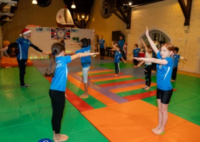 Children warming up with coach during gymnastics class in Kensington London