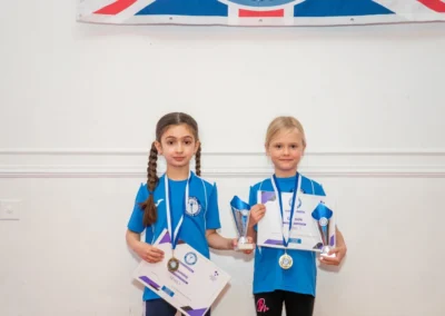 Children holding gymnastics certificates and trophies at Knightsbridge Gymnastics More House School SW1X