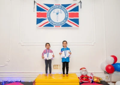 Two young gymnasts on awards podium at KCGA Christmas 2024 Knightsbridge gymnastics event at More House School SW1X