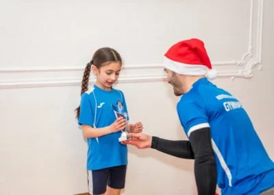 Gymnastics coach presenting a trophy at KCGA Knightsbridge Christmas awards at More House School SW1X London