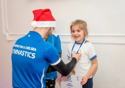 Coach awarding medal to child at Knightsbridge gymnastics Christmas 2024 at More House School SW1X London