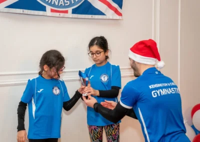 Coach presenting trophy to children at Knightsbridge gymnastics class at More House School SW1X London