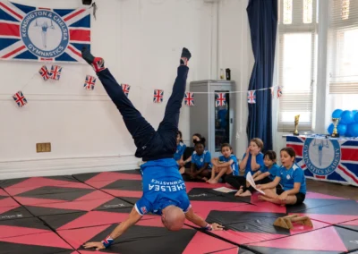 Coach Stefan Kolimechkov performing a headstand straddle demonstration for children at More House School, Knightsbridge London SW1X