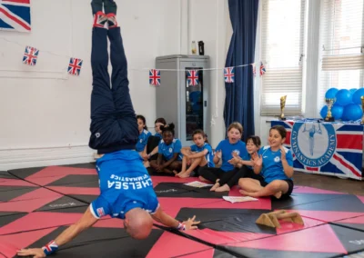 Stefan Kolimechkov holding a Japanese headstand as children clap at More House School, Knightsbridge London SW1X