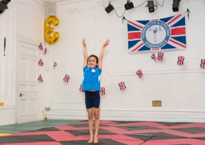 Young gymnast finishing routine with arms raised at KCGA Annual Performance Knightsbridge London