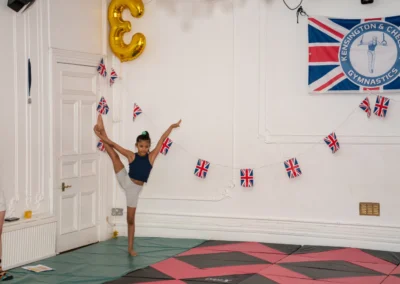 Young gymnast performing a high leg extension flexibility pose at More House School, Knightsbridge London SW1X