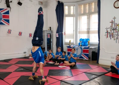 Coach Stefan Kolimechkov holding a handstand on parallettes at KCGA Annual Performance 2025 in Knightsbridge London