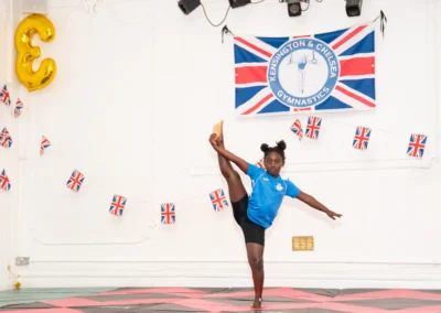 Young gymnast holding high leg extension at KCGA Annual Performance Knightsbridge London