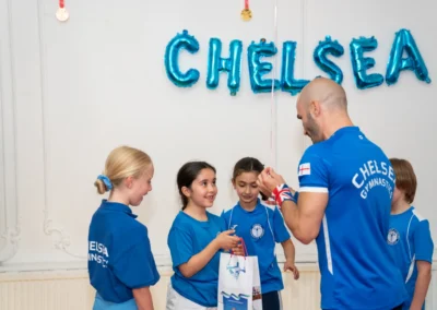 Coach Stefan presenting a medal to young gymnast at KCGA 2025 Annual Performance in Knightsbridge London at More House School SW1X