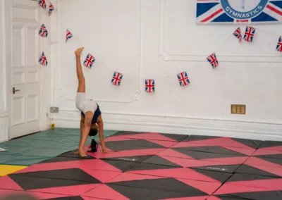 Young gymnast performing a walkover-style skill on mats at More House School, Knightsbridge London SW1X