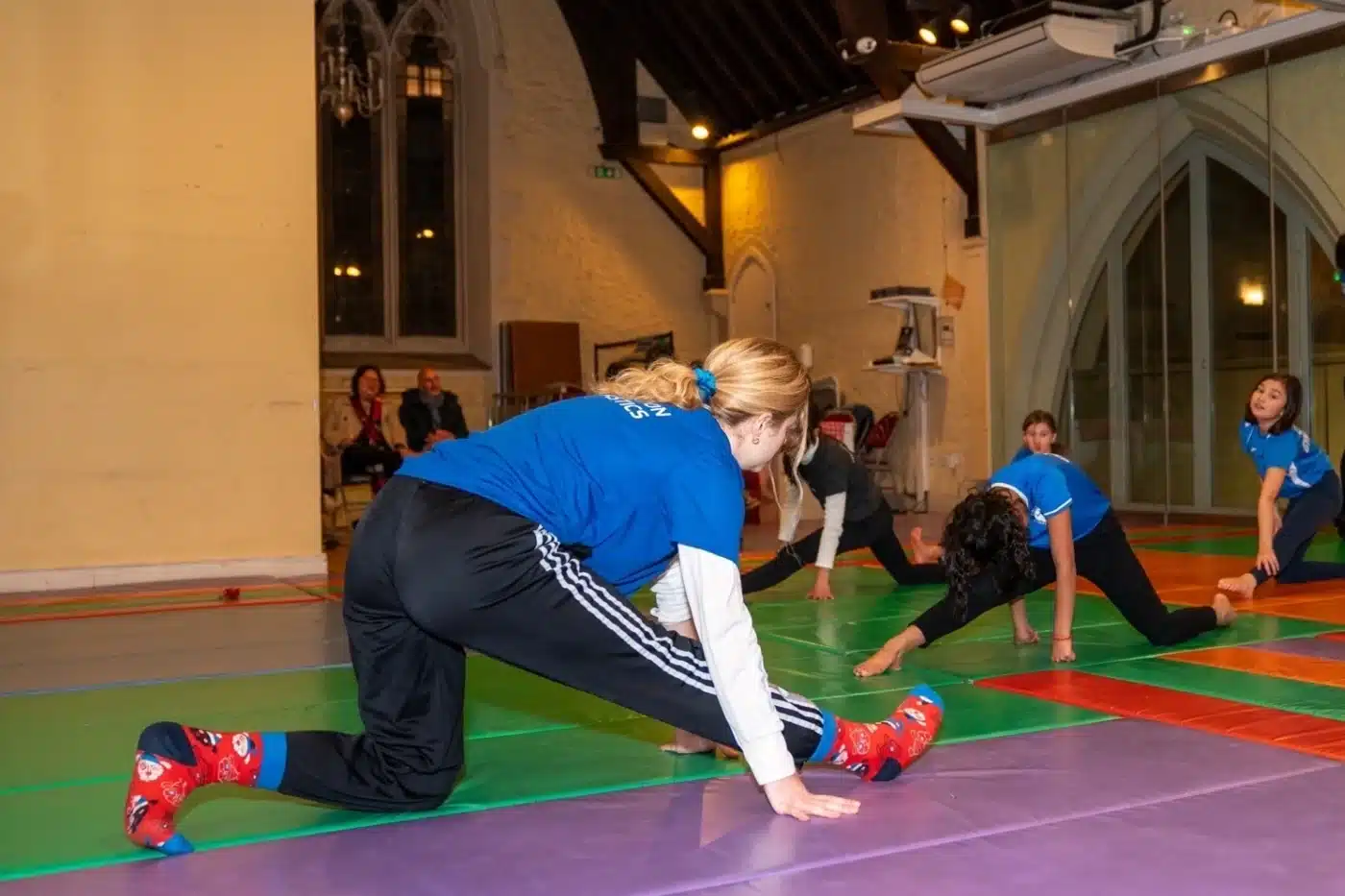Coach Venia leading a flexibility and stretching drill with children during a KCGA gymnastics class in London