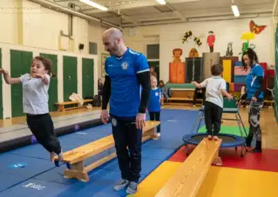 Young child jumping from a low balance bench during a KCGA Chelsea gymnastics class