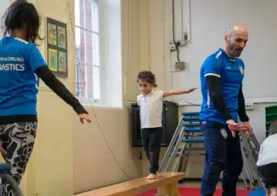 Young child walking along a low bench during a KCGA Chelsea gymnastics class for 4–6 year olds
