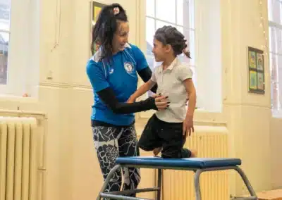 Young child learning how to do the gymnastics vault with coach support during Easter 2026 in Chelsea, London SW3