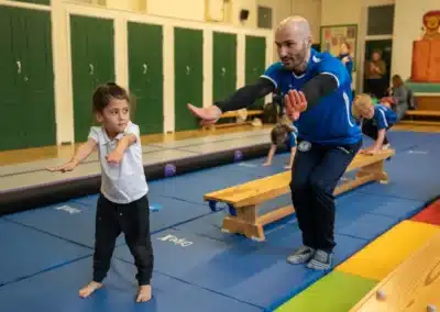 KCGA coach demonstrating the correct landing position to a young child during a Chelsea gymnastics class