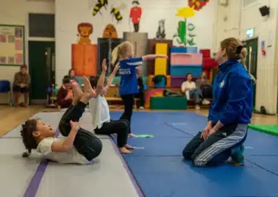 Young children practising a tucked rocking shape exercise during a KCGA Chelsea gymnastics class