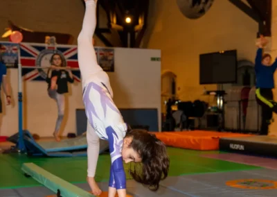 Child performing a cartwheel on a low balance beam during gymnastics training in Kensington London