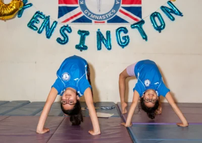 Two young gymnasts performing bridge poses during the KCGA Annual Performance 2025 in Kensington, London.