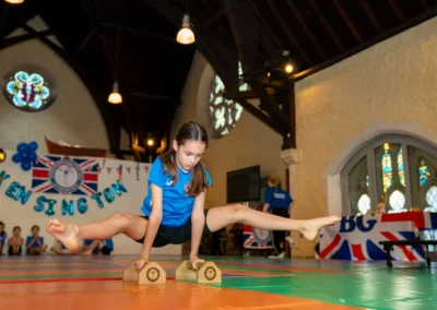 Young gymnast balancing on wooden hand blocks with legs extended during the KCGA Annual Performance 2025 in Kensington, London.
