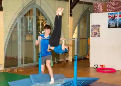 Young gymnast practising a back hip circle on the gymnastics bars with coach support at KCGA Kensington