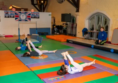 Children practising a hamstring stretch and flexibility exercise during KCGA Easter Week 2026 at St Philip’s Church in Kensington