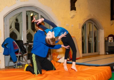 Young gymnast performing an assisted back handspring with coach support during gymnastics training in Kensington London