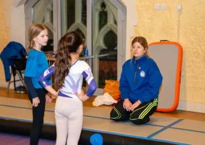 Gymnastics coach speaking to young gymnasts during training in Kensington London