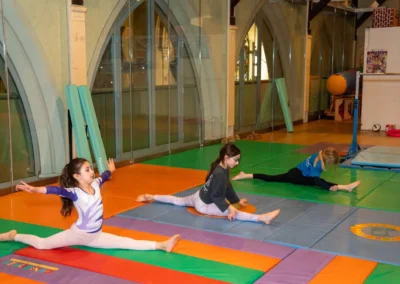 Children practising front splits and flexibility exercises during artistic gymnastics classes in Kensington London