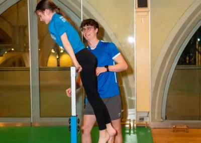 Girl practising support on gymnastics bars with coach guidance in Kensington London