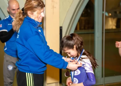 Coach presenting a medal to a young gymnast after gymnastics training in Kensington London