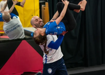 Dr Stefan Kolimechkov supporting a child performing a back tuck somersault during artistic gymnastics in Knightsbridge London