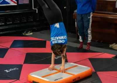 Child performing a round off on an inflatable air track during gymnastics in Knightsbridge London