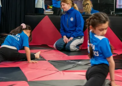 Children practising a split stretch with coach supervision during gymnastics classes in Knightsbridge London