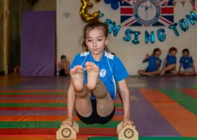 Young gymnast demonstrating strength and control on mini bars during the KCGA Annual Performance 2025 in Kensington, London.