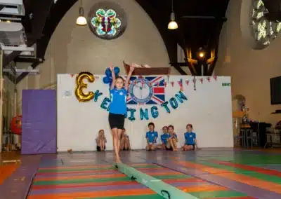 Young gymnast standing confidently on a balance beam during KCGA Annual Performance 2025 in Kensington.