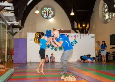 Gymnastics coach and young gymnast celebrating with a high five during KCGA Annual Performance 2025 in Kensington.