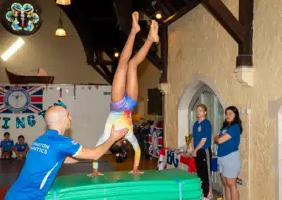 Gymnastics coach supporting a young gymnast during a handspring at KCGA Annual Performance 2025 in Kensington.