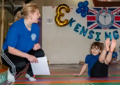 Gymnastics coach encouraging a young child during KCGA Annual Performance 2025 in Kensington, London.