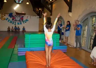 Young gymnast completing her gymnastics routine with a finishing salute during KCGA Annual Performance 2025 in Kensington, London.