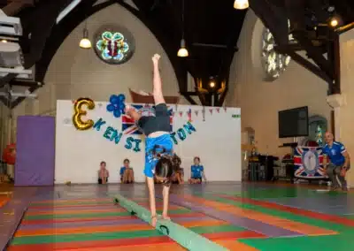 Young gymnast performing a handstand on a balance beam during the KCGA Annual Performance 2025 in Kensington, London.