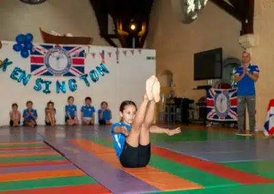Young gymnast performing V-sit balance during KCGA Annual Performance 2025 in Kensington, London.