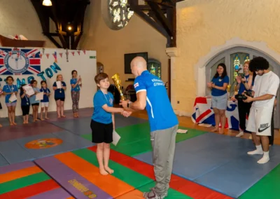 Young gymnast receiving an award trophy during KCGA Annual Performance 2025 in Kensington, London.