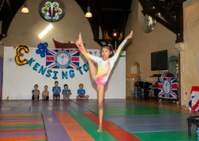 Female gymnast performing a standing leg Y-balance flexibility skill during KCGA Annual Performance 2025 in Kensington, London.