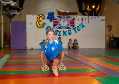 Kensington gymnast performing a front split stretch using training bars during KCGA Annual Performance 2025 in Kensington, London.